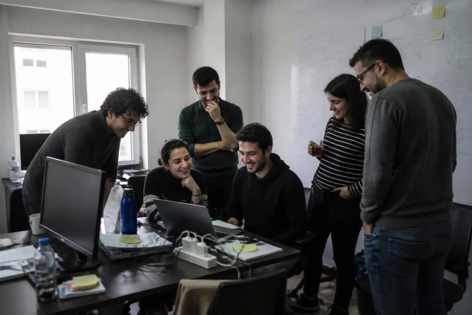 Developers gathered around a laptop, laughing